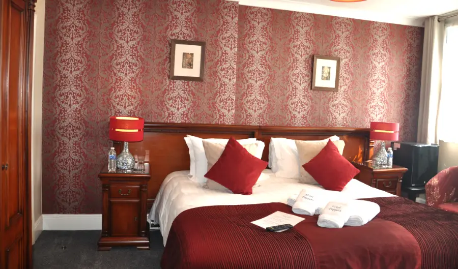 Semi Deluxe room with red bedding and patterned wallpaper